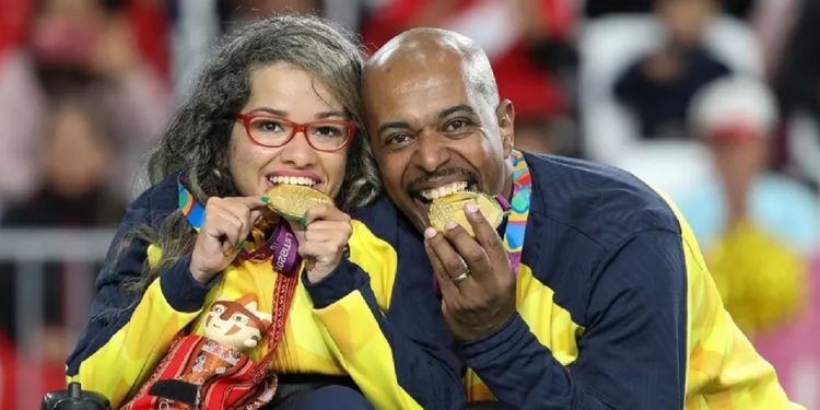 O calheiro Roberto Ferreira ao lado da atleta Evelyn Oliveira, da bocha. De costas para o jogo, ele ajusta a calha para os lançamentos da parceira. Foto: Daniel Zappe/EXEMPLUS/CPB